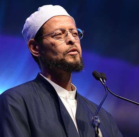 A man with glasses and beard wearing a white hat.