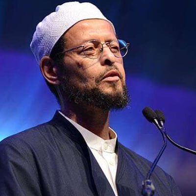 A man with glasses and beard wearing a white hat.