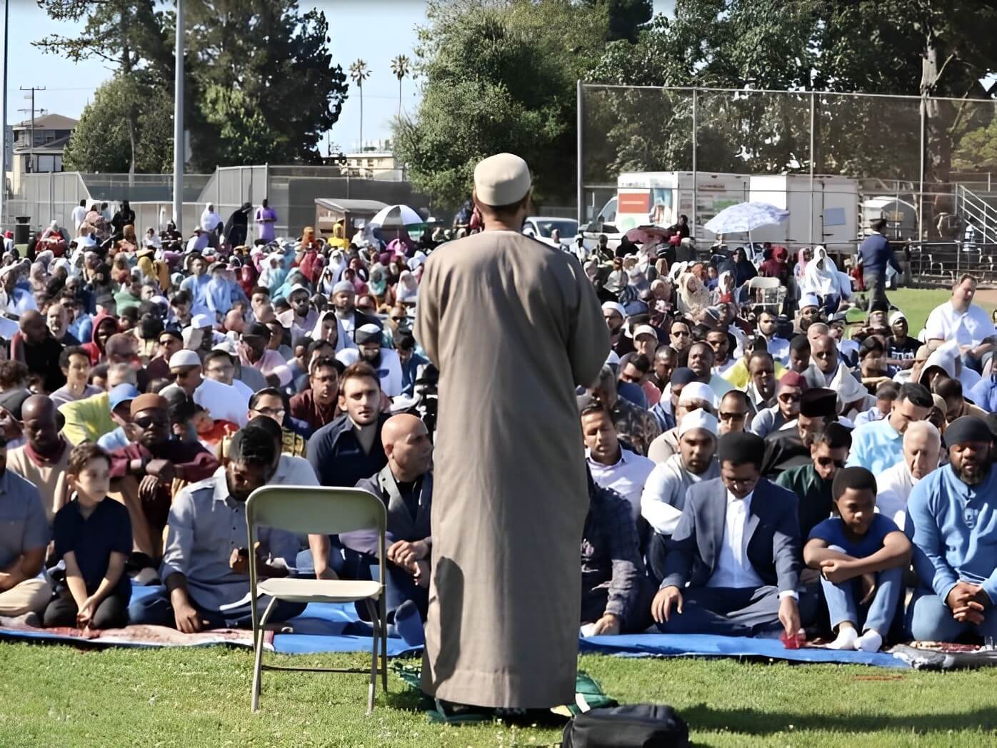 A man in a crowd of people sitting on the grass.